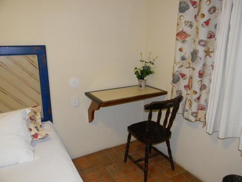 a bedroom with a table and a chair next to a bed at Pousada Recanto da Prainha in Torres