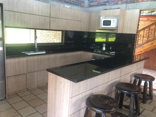 a kitchen with a counter with stools and a microwave at Chalet La Estancia - Parque del Café in Montenegro