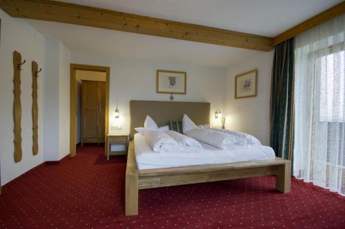 um quarto com uma cama com lençóis brancos e almofadas em Gästehaus Hackl em Sautens