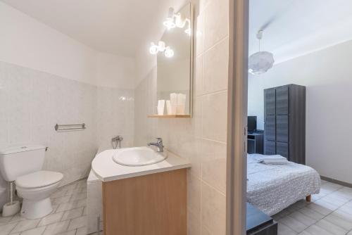 a white bathroom with a toilet and a sink at Hôtel du Rocher in Marseille