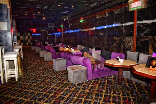 a restaurant with purple couches and tables in a room at Romance Alexandria Hotel in Alexandria