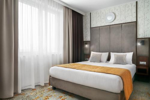 sypialnia z dużym łóżkiem i dużym oknem w obiekcie Metropolo by Golden Tulip Krakow w Krakowie
