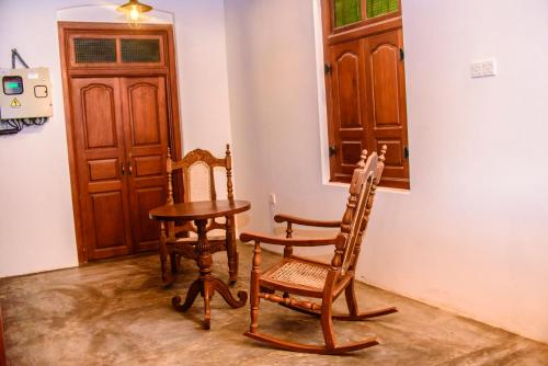 a room with a table and two chairs and a door at Thambu Illam in Jaffna