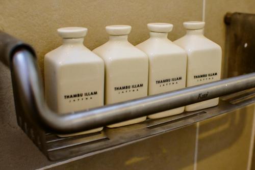 a group of four milk bottles on a shelf at Thambu Illam in Jaffna