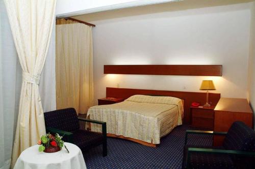 a hotel room with a bed and two chairs and a table at HOTEL CHELIA in Batna