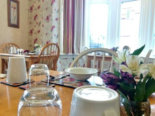 a wooden table with a vase of flowers on it at Rutland West Guest House in Filey