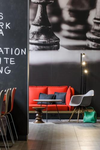 a red couch in a room with a table and chairs at Ibis Münster City in Münster