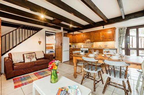 cocina y sala de estar con mesa y sillas en Berehayes Holiday Cottages en Bridport