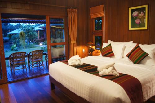 a bedroom with two beds and a balcony at Maikaew Damnoen Resort in Damnoen Saduak