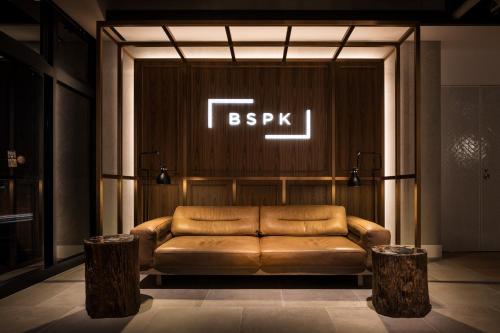 東京的住宿－Bespoke Hotel Shinjuku，墙上有标志的真皮沙发