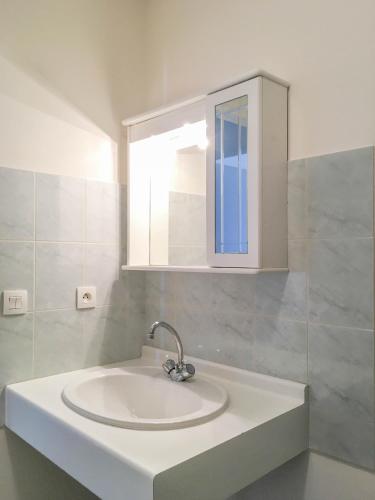 a white bathroom with a sink and a mirror at City Résidence Avignon in Avignon
