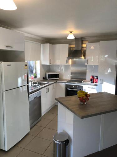 a kitchen with white appliances and a bowl of fruit on a counter at Glenelg Street in Perth