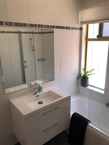 Un baño con lavabo, espejo y bañera. en Glenelg Street, en Perth