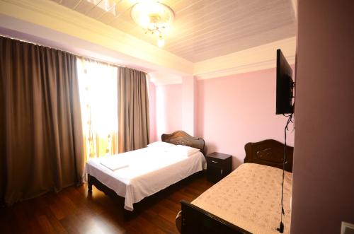 a hotel room with two beds and a window at Hotel Peria in Batumi