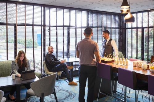 a group of people standing around a table in an office at Novotel Coventry in Coventry