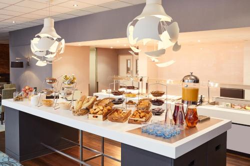 a breakfast buffet with pastries and drinks on a counter at Novotel Coventry in Coventry