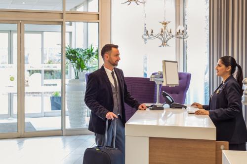 a man and a woman standing at a cash register at Novotel Coventry in Coventry