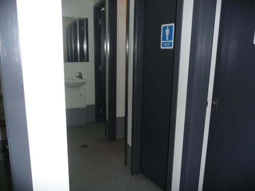 a hallway with a bathroom with a toilet and a sink at Mount Backpackers in Mount Maunganui