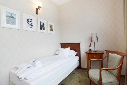 ein Schlafzimmer mit einem Bett und einem Stuhl sowie Bildern an der Wand in der Unterkunft Versant Hotel & Spa in Dzierżoniów