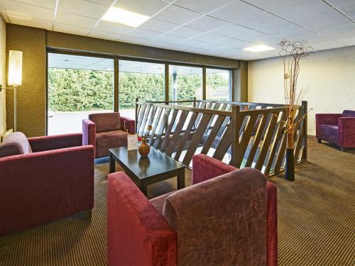 a waiting room with couches and chairs and a staircase at Kyriad Auxerre Appoigny in Appoigny