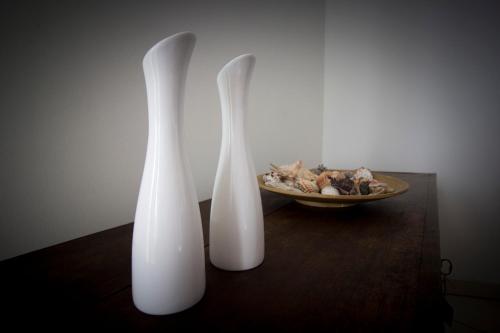 two white vases sitting on a table next to a plate at FIDES ON THE LAKE in Marone