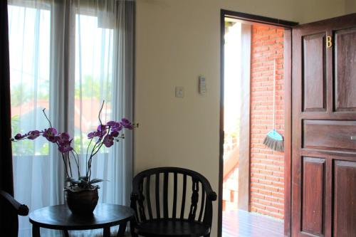 a table with a vase of flowers on it next to a door at Villadevi in Pangandaran