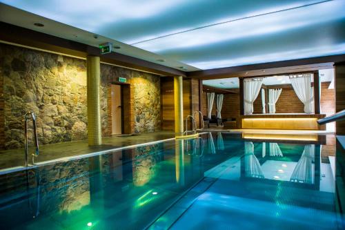 a swimming pool in a house with a stone wall at Hotel Aubrecht Country Spa Resort in Przechlewo