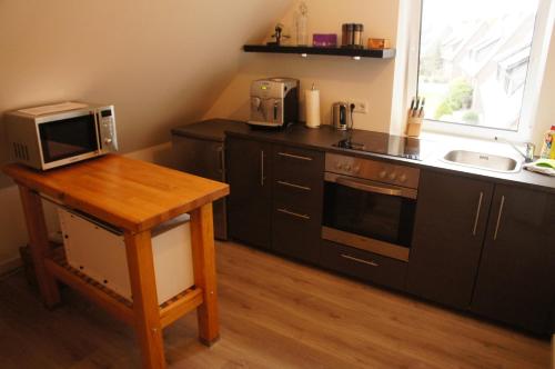 a kitchen with black cabinets and a microwave and a table at Dachstudio Bisping33 in Ascheberg