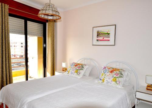 1 dormitorio con cama blanca y ventana en Casa do Mar, en Costa da Caparica