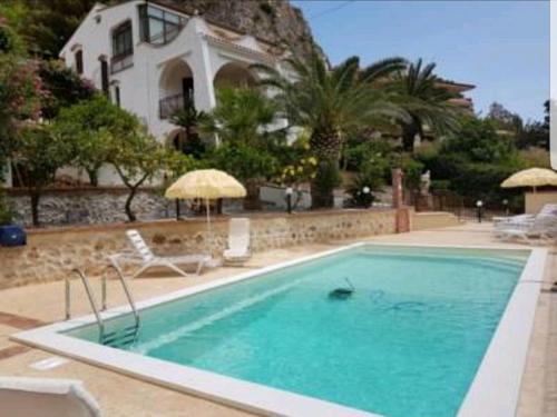 a swimming pool in front of a house at Villa del Golfo Urio with swimming pool shared by the two apartments it is essential to have a car in Santa Flavia