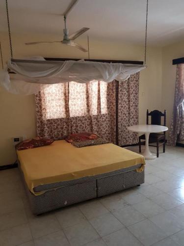 a bedroom with a bed with a canopy and a table at Surahi Restaurant & Guest House in Malindi