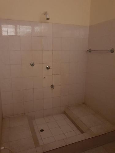 a bathroom with a shower with a tiled floor at Surahi Restaurant & Guest House in Malindi