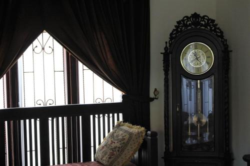 a grandfather clock sitting in a room with windows at Villadevi in Pangandaran