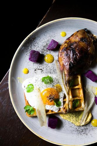 a plate of food with a chicken and eggs and waffles at Hotel Aubrecht Country Spa Resort in Przechlewo