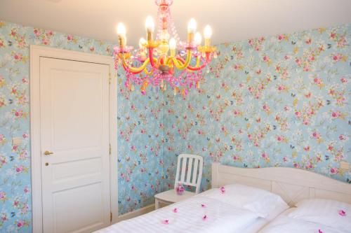 1 dormitorio con lámpara de araña y papel pintado con motivos florales en 'Hof der Heerlijckheid' en Borgloon