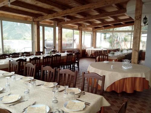 una sala da pranzo con tavoli, sedie e finestre di Locanda Adele a Parghelia