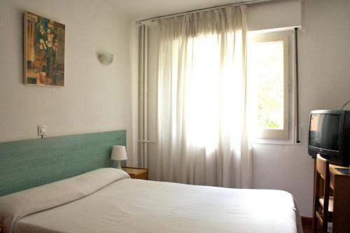 Schlafzimmer mit einem Bett, einem Fenster und einem TV in der Unterkunft Siracusa in Andorra la Vella