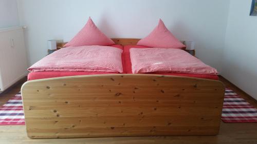 uma cama de madeira com duas almofadas cor-de-rosa em Martina's place em Rottenbuch