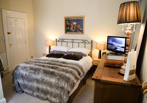 a bedroom with a bed and a desk with a television at The Villa Bridlington in Bridlington
