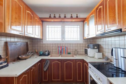 a kitchen with wooden cabinets and white counter tops at Country Rooms near Athens - Airport in Vravrona