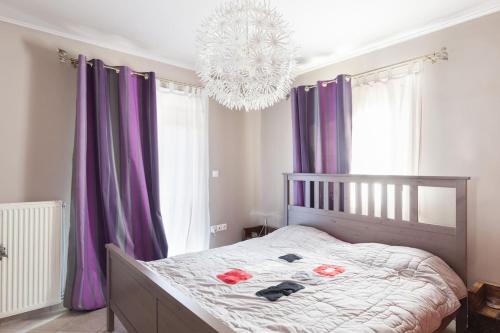 a bedroom with a bed with purple curtains and a chandelier at Country Rooms near Athens - Airport in Vravrona