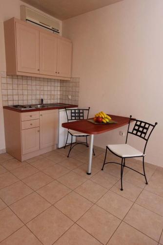 a kitchen with a table and two chairs and a table with bananas on it at Lambrinos Suites in Plataniás
