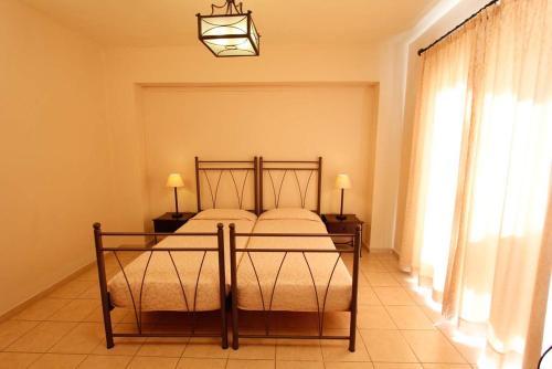 a bedroom with a bed with two tables and a window at Lambrinos Suites in Plataniás
