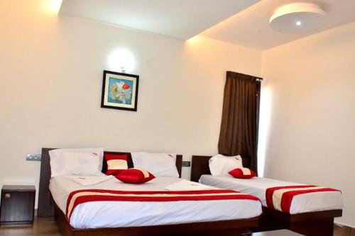 a hotel room with two beds with red pillows at Kodai Drizzle - A Luxury Villa in Kodaikānāl