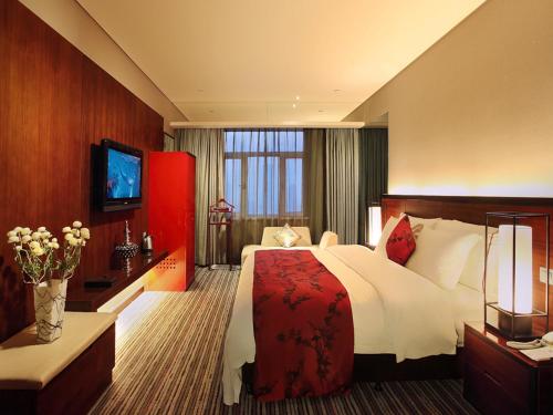 天津市にあるグランド ビュー ホテル ティアンジンの大型ベッドとテレビが備わるホテルルームです。