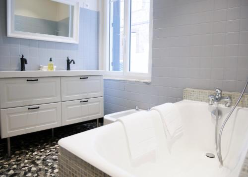 a bathroom with a white tub and a sink at La Famiglia in Étretat