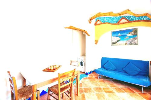uma sala de estar com um sofá azul e uma mesa em Orosei RE - Il Paradiso degli Ulivi con vista mare em Orosei