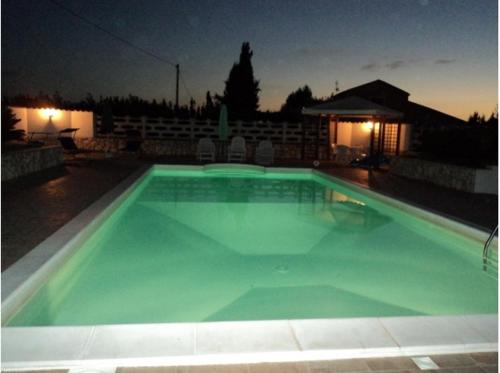 a large swimming pool with green water at night at Residenza agrituristica Santa Lucia con piscina in Alghero