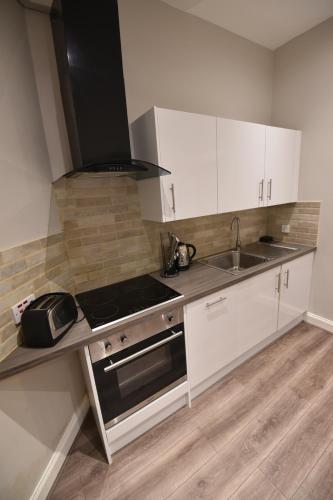 a kitchen with white cabinets and a sink and a stove at Slateford House Apartment Ground Floor Main Door in Edinburgh