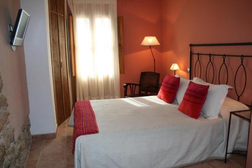 a bedroom with a large white bed with red pillows at La Alquería in Ráfales